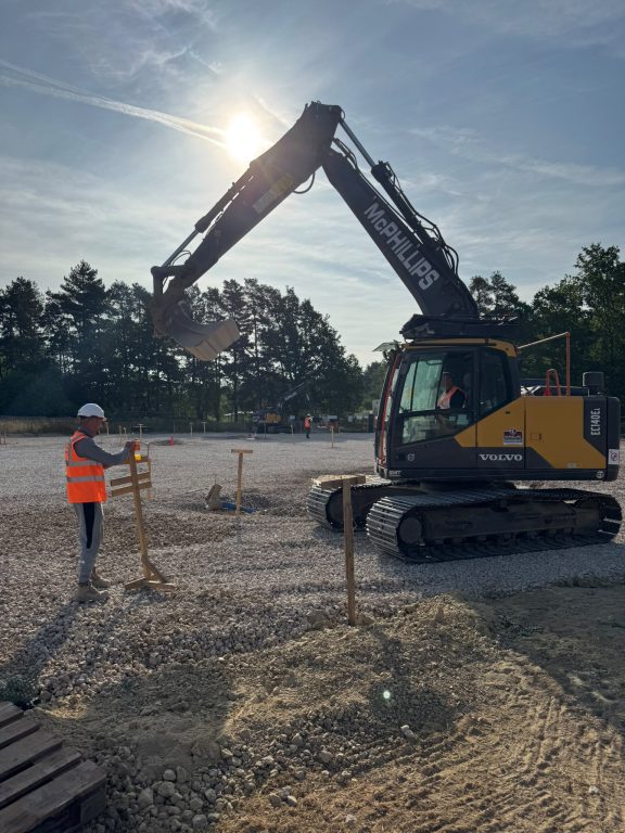 A workman standing next to a digger.